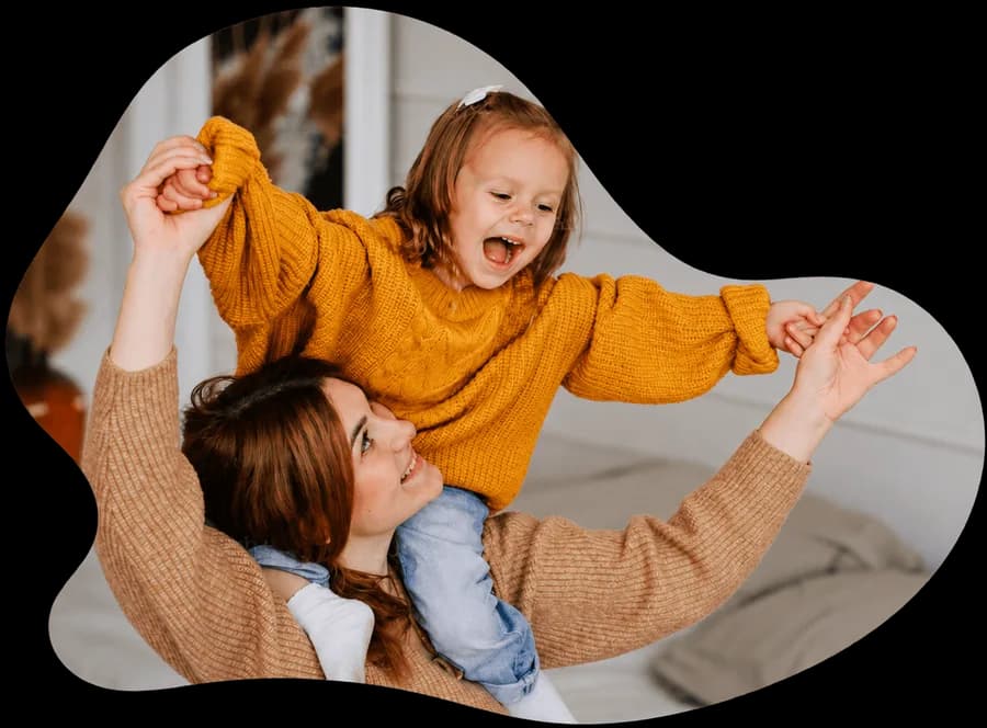 A mom playing with her laughing daughter on her shoulders